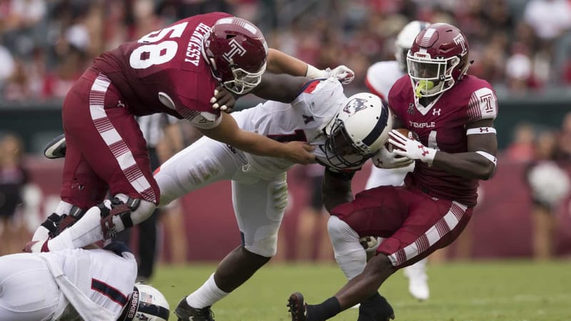 PHILADELPHIA, PA - OCTOBER 14: David Hood #24 of the Temple Owls runs with the ball and is tackled by Junior Joseph #11 of the Connecticut Huskies while Matt Hennessy #58 of the Temple Owls tries to block in the second quarter at Lincoln Financial Field on October 14, 2017 in Philadelphia, Pennsylvania.